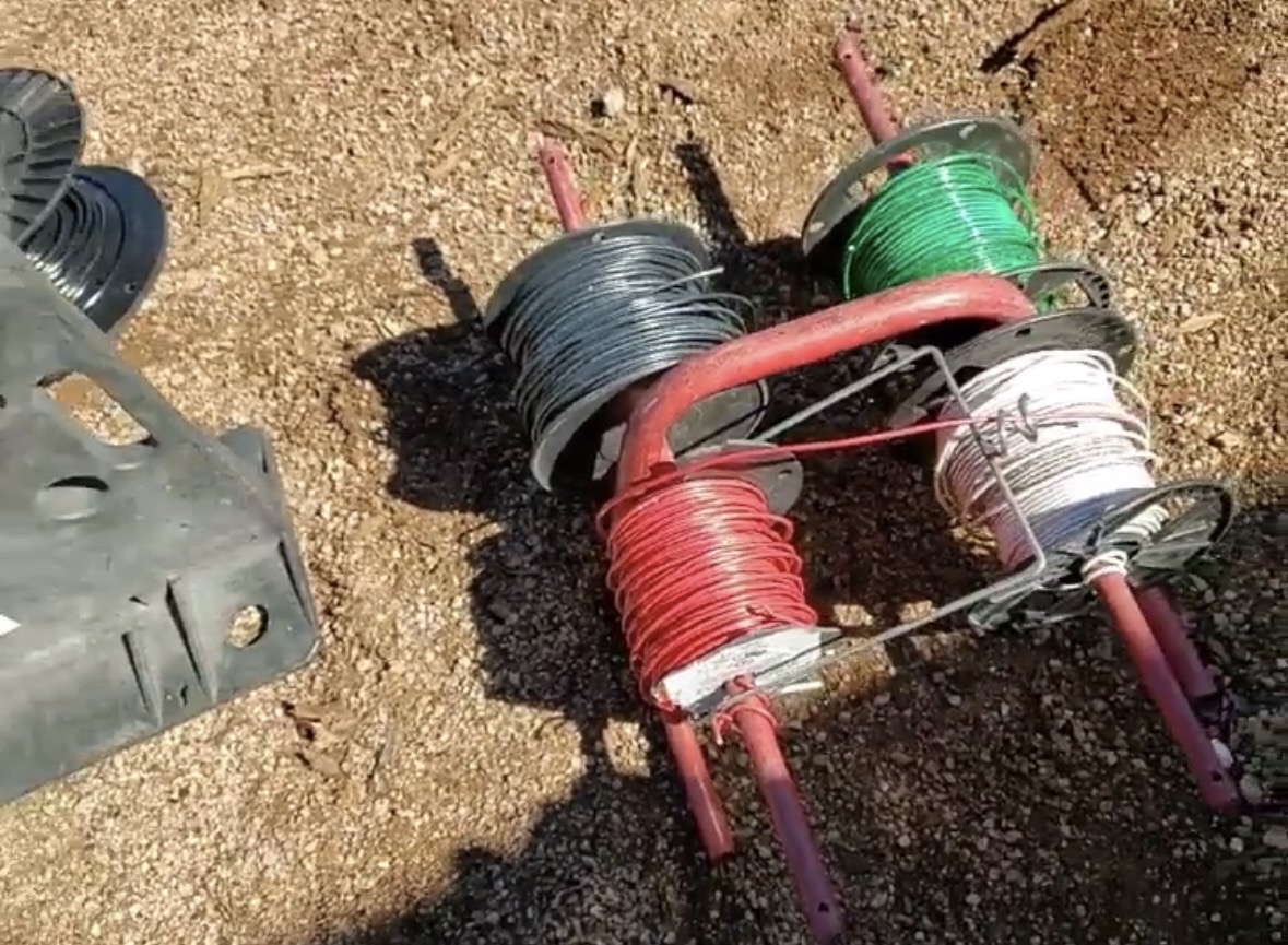 SpoolPig on a jobsite hand cart loaded with black, green, red, and white wire spools ready to pull